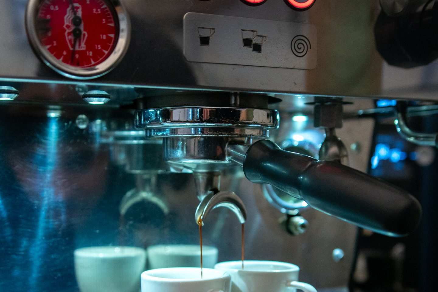 Espresso läuft aus einem Siebträger in zwei weiße Tassen
