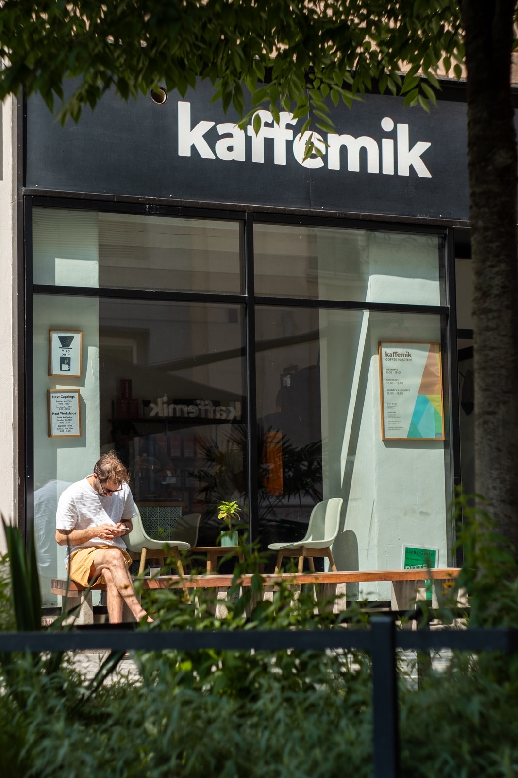 Die Fassade des Kaffemik Cafés in Wien mit Gast auf der Bank davor